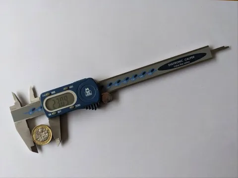Measuring a UK pound coin using a set of digital callipers.